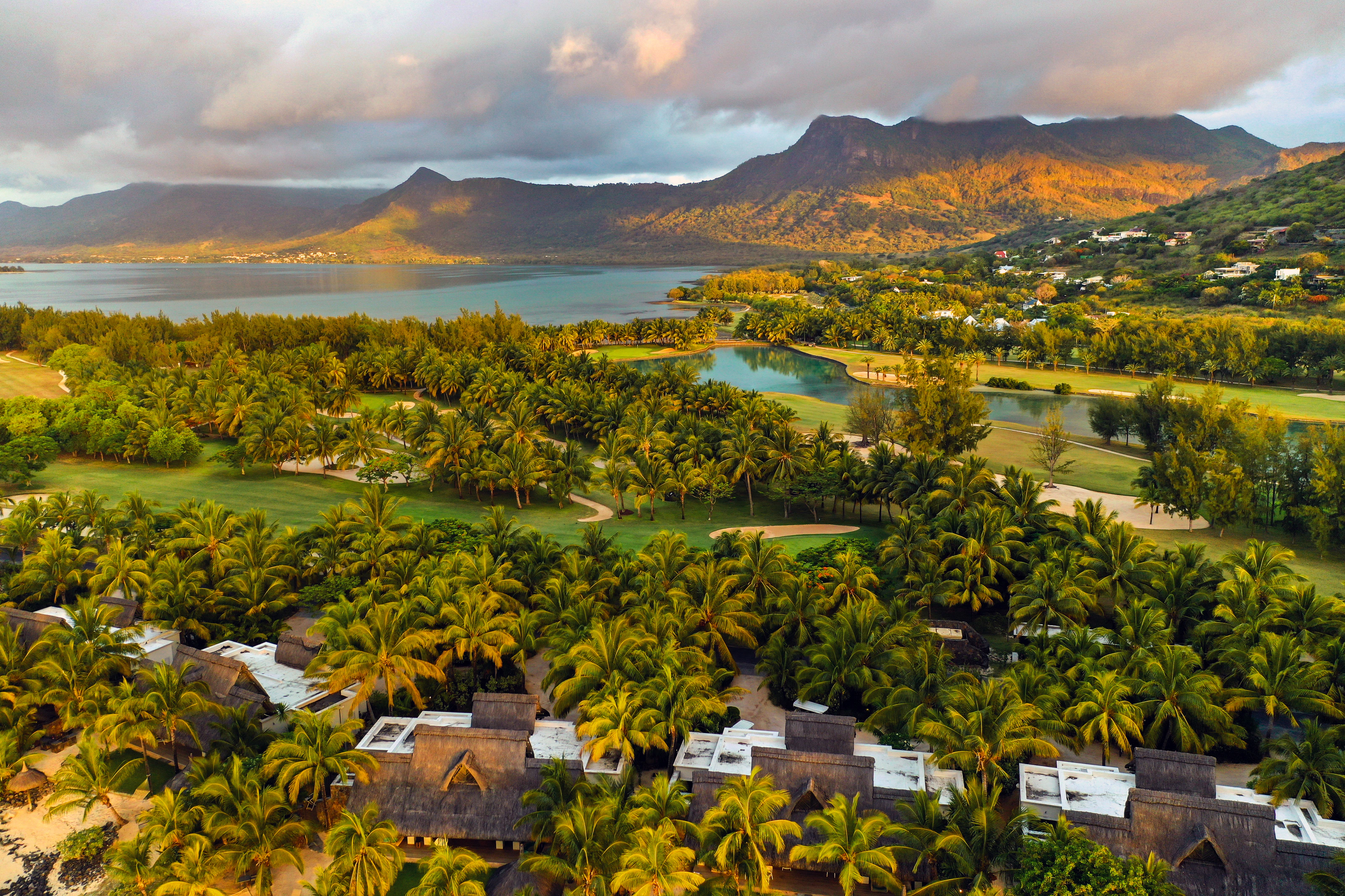 Vue aérienne de la péninsule du Morne, à l’île Maurice : le lagon, un parcours de golf et des villas en fin de journée.